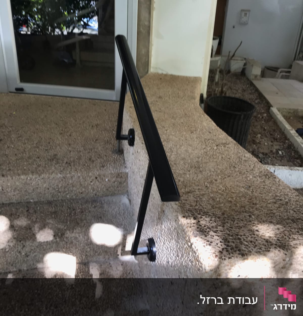 מעקה שחור על מדרגות אבן ליד דלת זכוכית